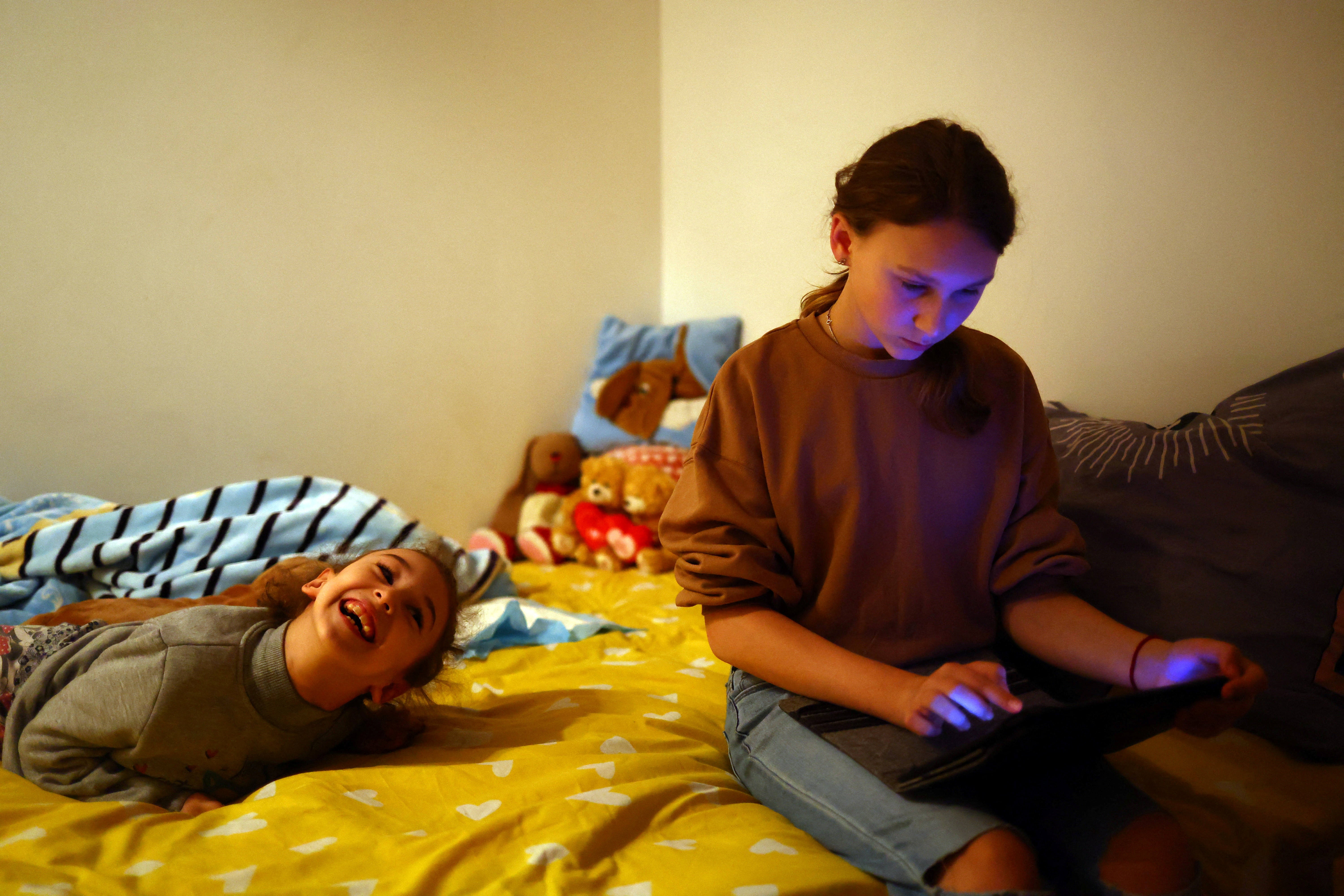 Viktoria Bravorichenko, 12, sits on the bed with her sister, Alevtina, in their bedroom