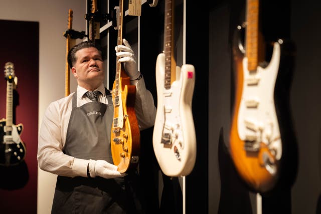 An art handler holds a 1959 Gibson Les Paul known as Yardburst during the photocall for the Jeff Beck: The Guitar Collection at Christie’s in central London (James Manning/PA)