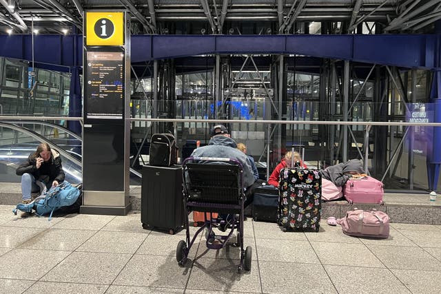 <p>Going nowhere: Passengers outside London Heathrow airport Terminal 5 on 21 March</p>