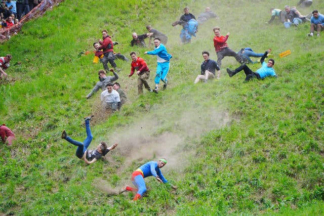 <p>Participants take part in the annual cheese rolling at Cooper’s Hill in Brockworth, Gloucestershire (Ben Birchall/PA)</p>