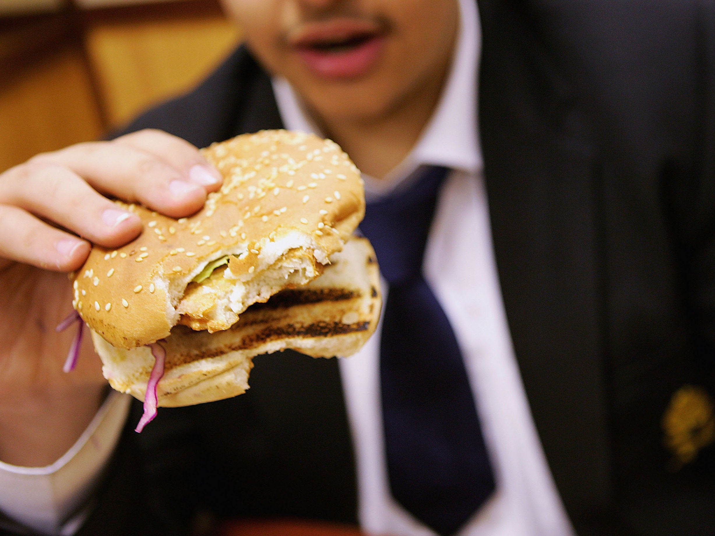 In this photo illustration a school student eats a hamburger as part of his lunch which was brought from a fast food shop near his school, on October 5, 2005 in London, England. The British government has announced plans to remove junk food from school lu